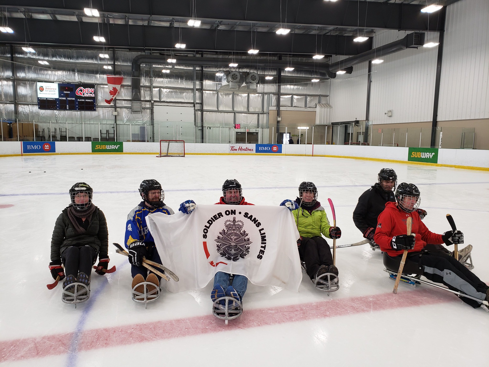 Six Soldier On members on sledge hockey gear holding a Soldier On flag.